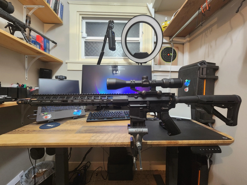 AR-15 sitting on a vice, clamped to an office desk.